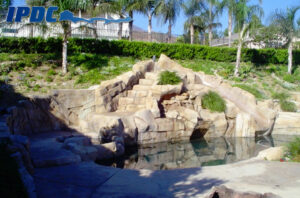 Photograph of a large-scale residential construction project of an outdoor swimming pool with rock formation slide.