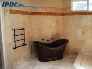 Renovated bathroom with tile walls and matching floor and bronze tub.