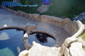 Photograph of a large-scale residential construction project of an outdoor swimming pool with rock formation slide.