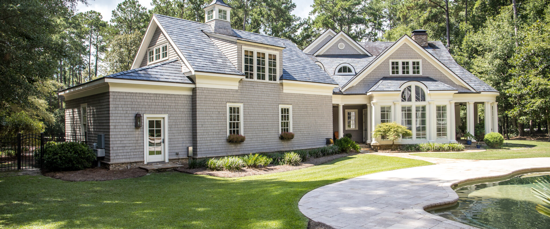 Rear view and backyard of large cape cod style home with columns